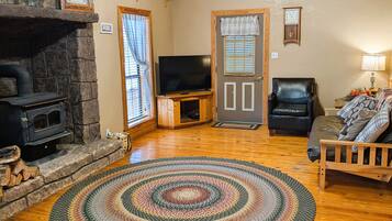 Una sala de estar acogedora con chimenea, televisor y techo de madera.