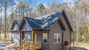 A two-story cabin with a front porch, a small deck, and a chimney.