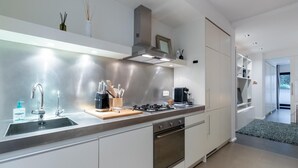 Eine moderne Küche mit Edelstahlgeräten, einem eingebauten Backofen und einer Kaffeemaschine.