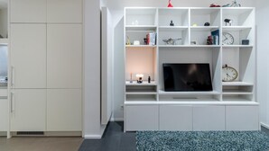 Ein modernes Wohnzimmer mit einer weißen Unterhaltungsanlage, einem Flachbildfernseher und einem Bücherregal.