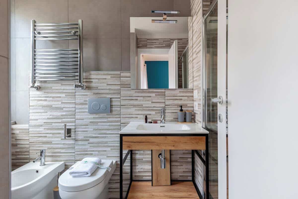 Une salle de bain moderne avec une baignoire sur pieds, un lavabo doté d’un plan de toilette en bois et un porte-serviettes.