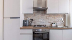 Une cuisine compacte équipée d’une cuisinière à gaz, d’un four et d’un crédence moderne.