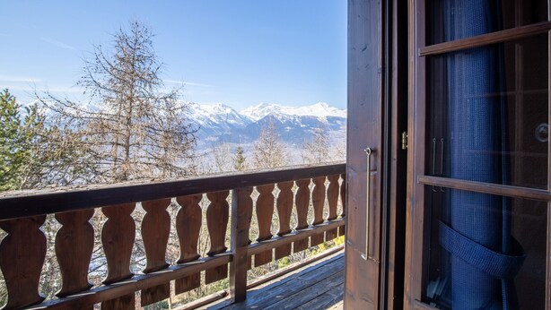 Un balcón de madera con vistas a montañas nevadas.