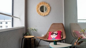 A small balcony with a wooden ceiling, a wicker chair with a cushion, a small table, and a potted plant. - STUDIO.LOFT.MOUNTAINS (Collombey-Muraz)