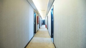 Un pasillo largo y estrecho con puertas a ambos lados que dan a habitaciones individuales.