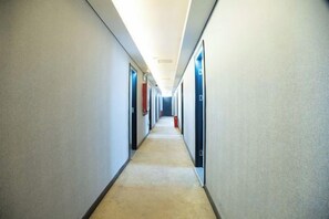 Un largo y estrecho pasillo de hotel con puertas a ambos lados, que conduce a habitaciones individuales.