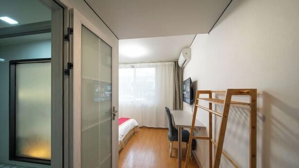 Habitación de hotel con cama, escritorio, silla, televisor y ventana con cortinas.