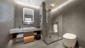 A modern bathroom with a glass-enclosed shower, a large mirror, and a white toilet.
