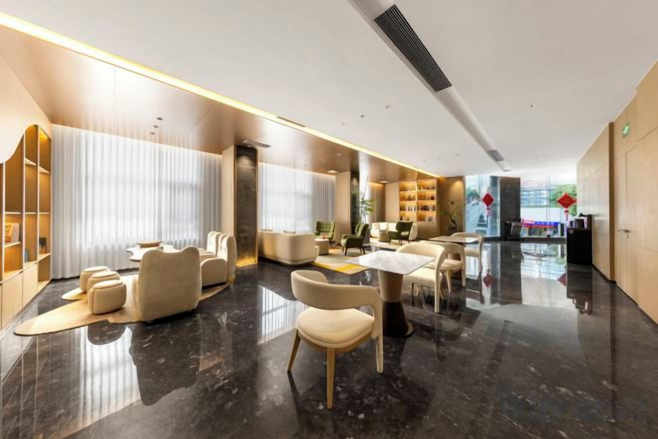 A modern hotel lobby with a marble floor, leather seating, and a reception desk.