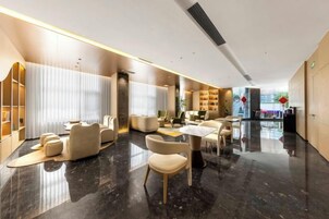Un moderno vestíbulo de hotel con piso de mármol, asientos de cuero y una recepción.