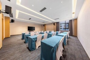 A conference room with tables and chairs, a flat-screen TV, and a large window. - Huaxi Hotel (Nayong)
