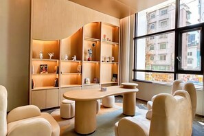 A modern interior with a curved bookshelf, a round table, and comfortable seating. - Huaxi Hotel (Nayong)