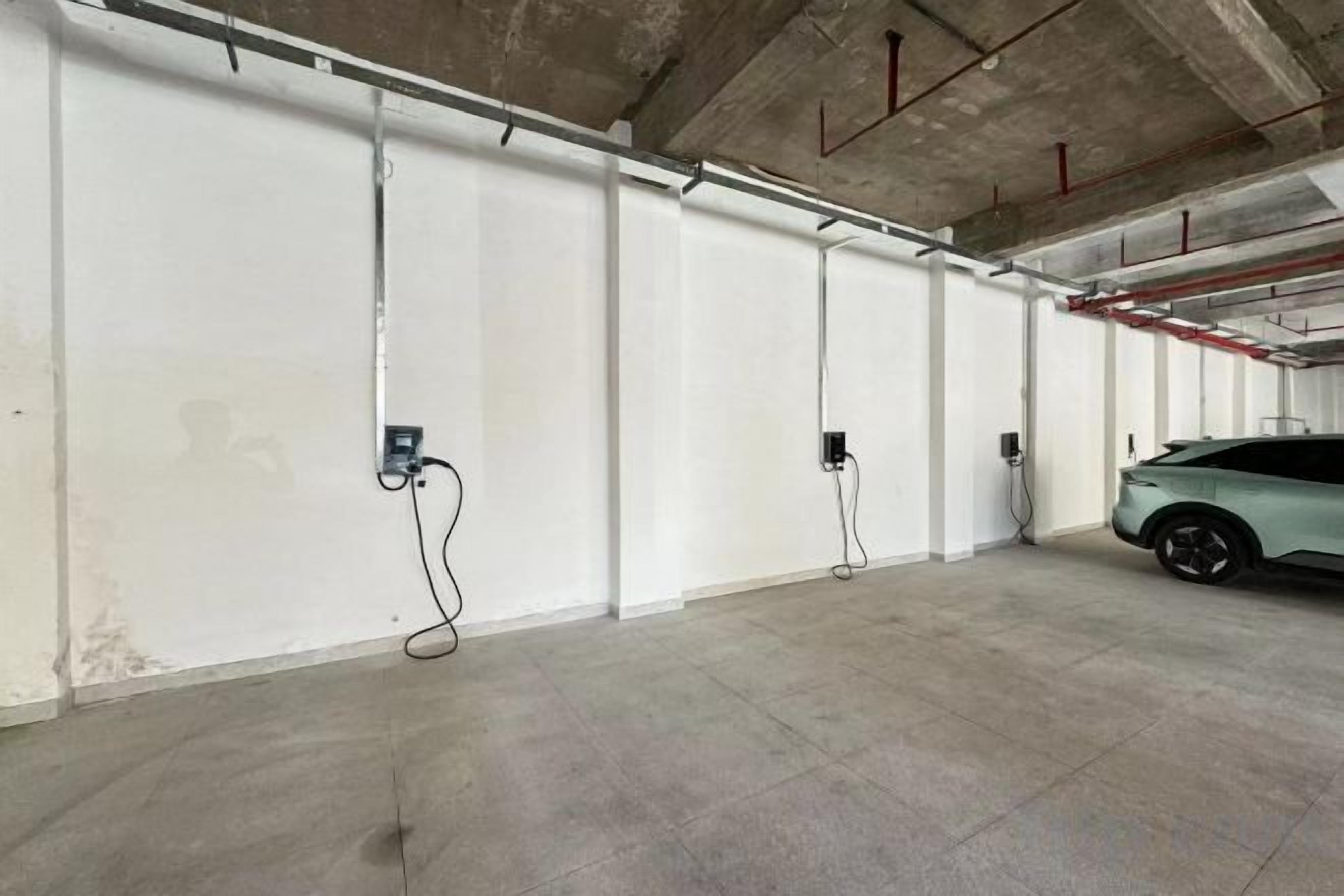 A parking garage with concrete floors and walls, equipped with electric vehicle charging stations.