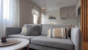A modern living room with a grey sofa, a round white coffee table, and a wooden floor. - Charming and bright T3 completely renovated, located 10 minutes walk from downtown. (Gijón)