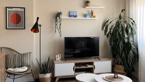 A modern living room with a TV, sofa, and a large plant. - Charming and bright T3 completely renovated, located 10 minutes walk from downtown. (Gijón)