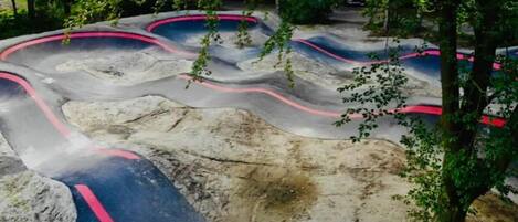 A winding outdoor track with red and blue painted lines, surrounded by trees.