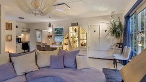 Un salon moderne avec un canapé, un coin repas et une cuisine en arrière-plan.