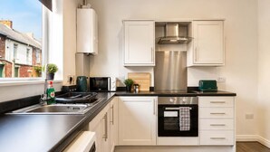 Eine moderne Küche mit weißen Schränken, einer Edelstahl-Dunstabzugshaube, einer Mikrowelle und einem Backofen.