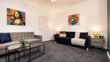A modern living room with two sofas, a coffee table, and artwork on the walls.