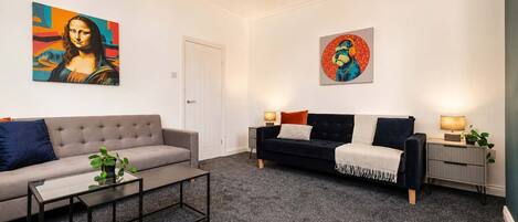 A modern living room with two sofas, a coffee table, and artwork on the walls.