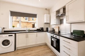 A modern kitchen with a washing machine, a microwave, and a toaster. - Spacious 3BR in Blyth | Sleeps 6 | By Stay With Us (Northumberland)