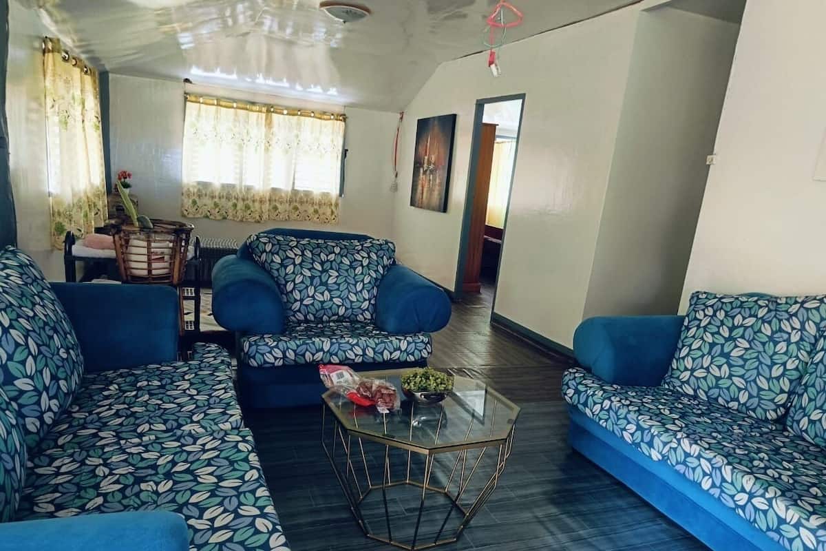 Sala de estar com sofás azuis e uma mesa de centro de vidro.