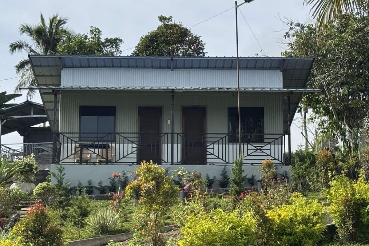 Um edifício térreo com telhado plano, duas portas visíveis e uma pequena varanda com grade.