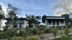 A modern two-story building with a balcony, surrounded by lush greenery and a variety of plants. - Helens Mountain Resort (Arakan)