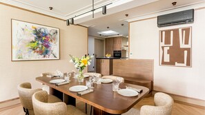 Un comedor con una larga mesa dispuesta para seis personas, flanqueada por sillas, y un jarrón con flores sobre la mesa.