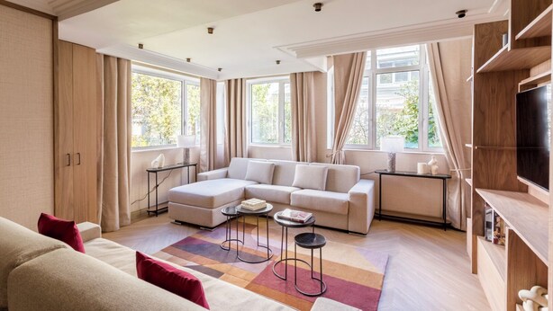A modern living room with a sectional sofa, a coffee table, and a TV on a wooden shelf. - Merveil - Signature Suite - Tour Eiffel - Viala IV (Paris)