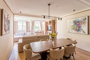 A modern living room with a dining area, a sofa set, and a TV.