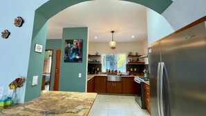 Una cocina moderna con una isla central, un refrigerador y un comedor con mesa de mármol.