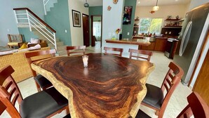 Un comedor con una amplia mesa de madera, sillas y una escalera que sube a otro nivel.