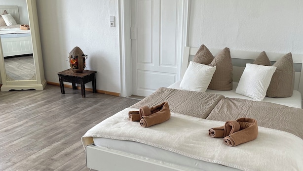 Un dormitorio con cama, almohadas, mesita de noche, espejo y puerta.