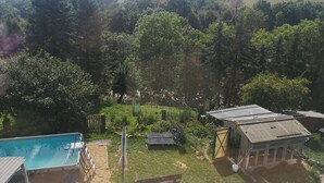 Un patio trasero con piscina, una terraza de madera y un cobertizo pequeño.