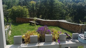 Un jardín con un muro de piedra, un banco de madera y diversas plantas.