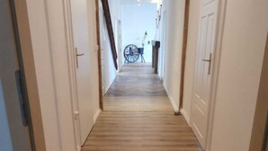 Un pasillo con suelo de madera y un felpudo al final.