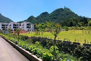 A residential area with modern buildings, a well-maintained lawn, and a mountain backdrop. - Tiantai Happiness Inn (Tiantai County)