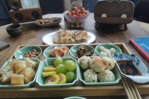 A wooden table with various dishes and a bowl of fruit. - Tiantai Happiness Inn (Tiantai County)