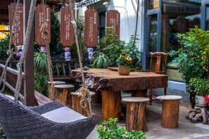 A wooden table with a rustic design, surrounded by wooden stools and a hanging chair. - Tiantai Happiness Inn (Tiantai County)
