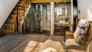 A bedroom with a bed, a wooden staircase, a bathroom, and a view of the outdoors. - Tiantai Happiness Inn (Tiantai County)