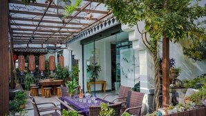 An outdoor patio with a dining area, potted plants, and a pergola structure. - Tiantai Happiness Inn (Tiantai County)