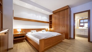 A modern bedroom with a wooden bed, nightstands, and built-in wardrobe.