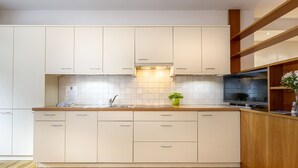 A modern kitchen with white cabinets, a wooden countertop, and a built-in oven.