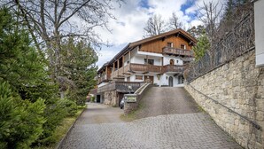 A traditional wooden building with balconies, a stone wall, and a paved pathway.