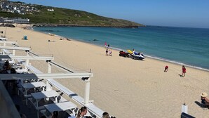 A beach with white lounge chairs and a view of the ocean. - Uno Moor Side (Carbis Bay)