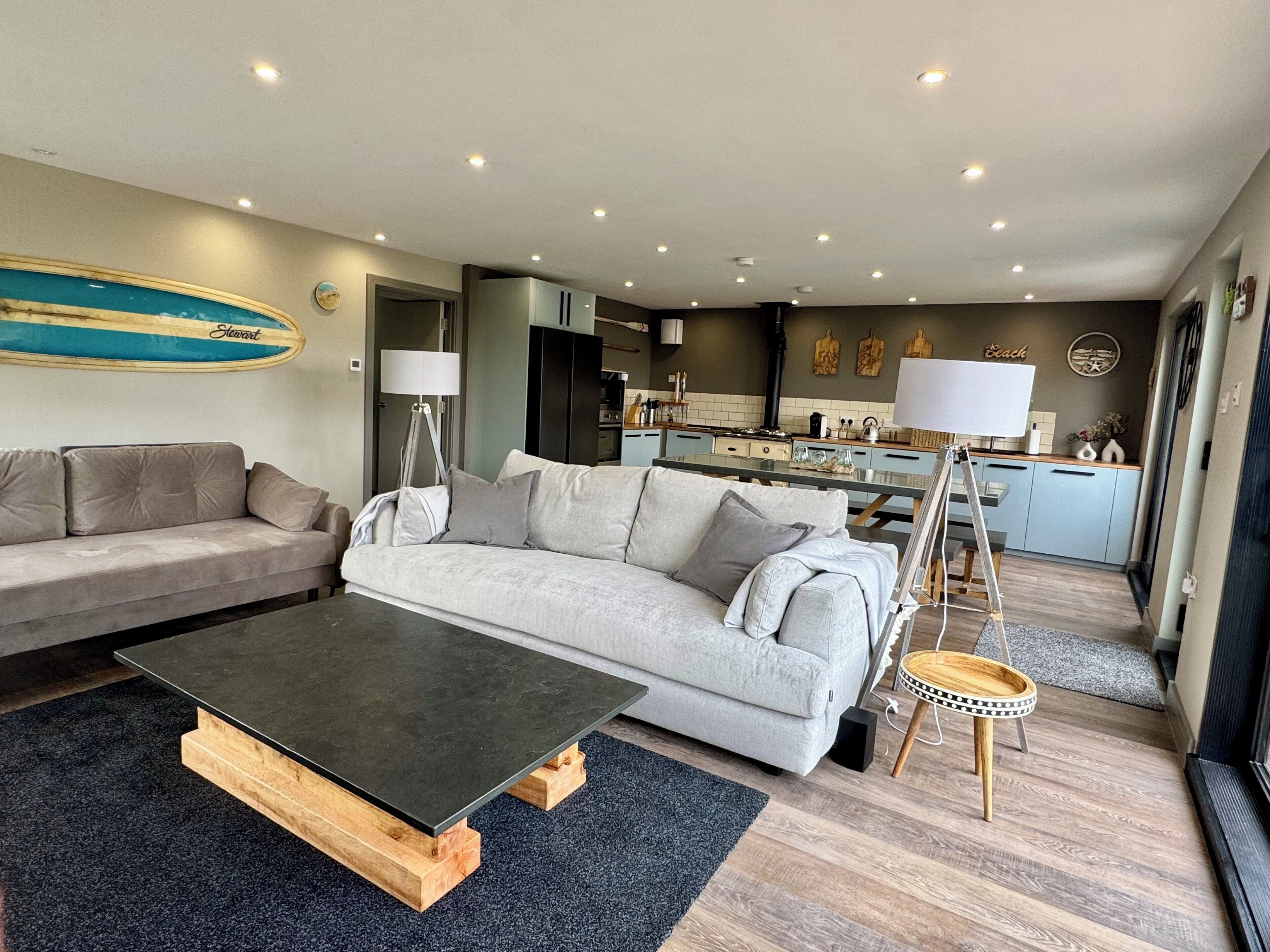 A modern living room with a sofa, a coffee table, and a kitchen in the background.