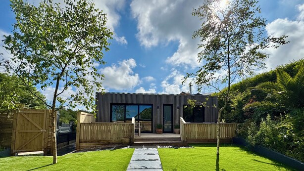 A modern house with a wooden deck, a paved pathway, and a well-maintained lawn. - Uno Moor Side (Carbis Bay)