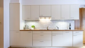 Une cuisine moderne avec des meubles blancs, un plan de travail en bois et un revêtement mural en carreaux.