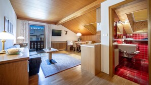 Un intérieur moderne avec un plafond en bois, un coin repas, une cuisine aux carreaux rouges et un téléviseur bien en évidence.